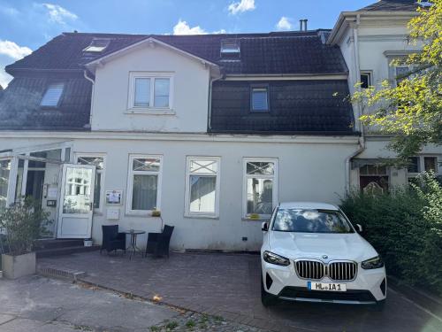 a white car parked in front of a white house at Pension Am Burgtor in Lübeck