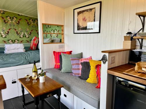 a small room with a bench with pillows and a table at Tŷ Ni Tiny Houses in Bridell