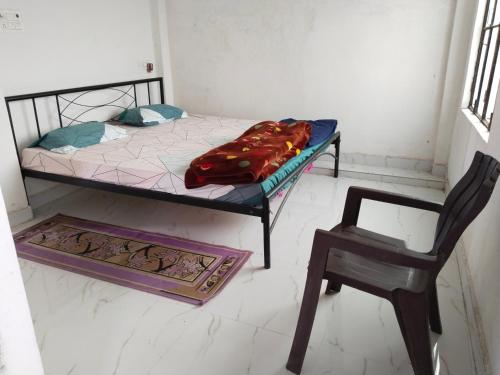 a bedroom with a bed and a chair and a table at Omkar Homestay in Prayagraj