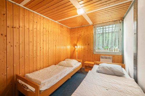 a bedroom with two beds in a wooden wall at Bungalow 30 - Kimbucht in Reichendorf