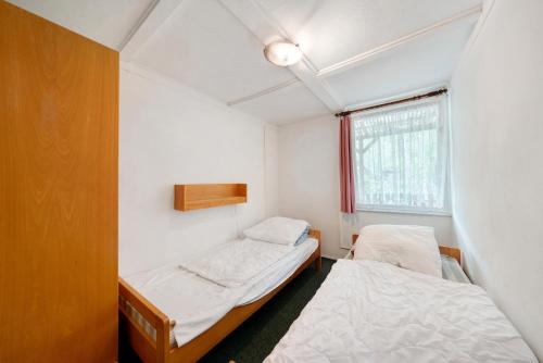 two beds in a small room with a window at Bungalow 33 - Kimbucht in Reichendorf