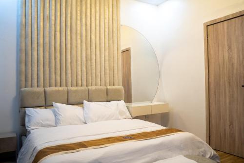 a bedroom with a large bed and a mirror at ScattHomes Lekki With Swimming Pool, PS5, Gym, Jacuzzi, Free Wifi and many more in Lekki