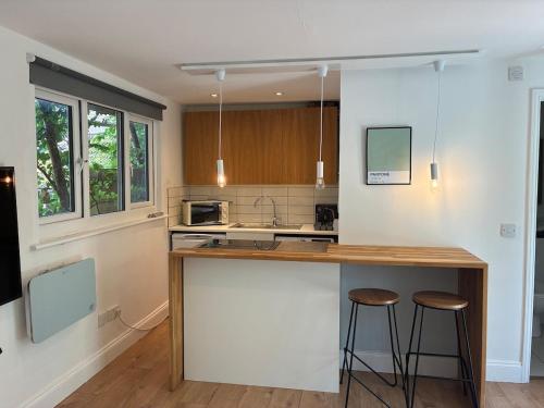 a kitchen with a counter and two bar stools at Self-contained studio with patio in Ware