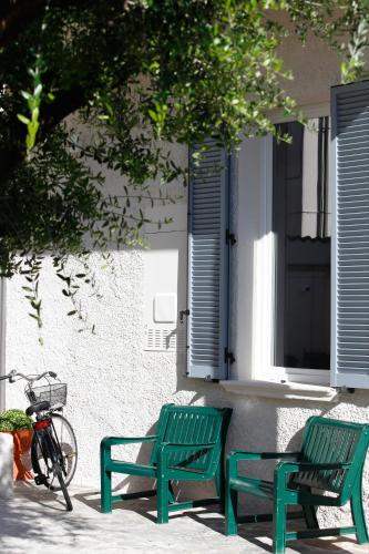 two green benches sitting next to a building with a bike at Casa da Victoria in Castrezatto