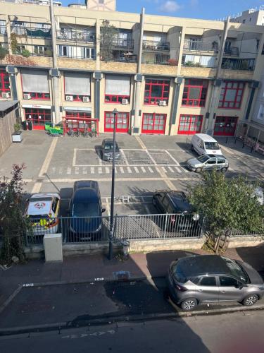 a parking lot with cars parked in front of a building at Appartement in Montreuil