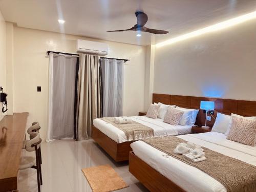 Un dormitorio con dos camas y un ventilador de techo. en Calathea Suites El Nido, en El Nido