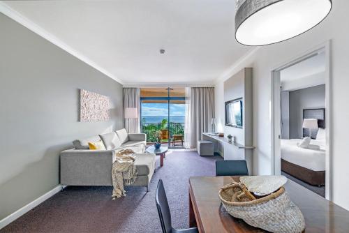 a living room with a couch and a bed at Esplanade Poolside Living with Lush Balcony Vistas in Darwin