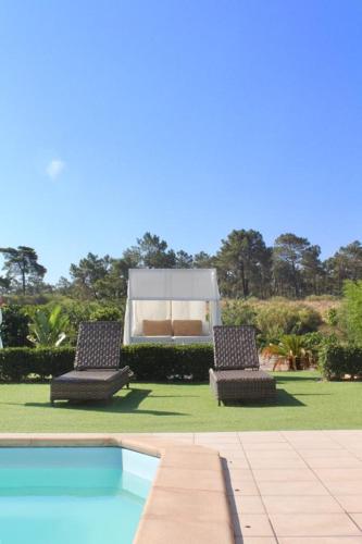 two chairs and a tent in a yard with a pool at Hotel Quinta Da Rosa Linda in Monte Gordo