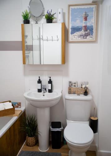 a bathroom with a sink and a toilet and a lighthouse at Norwich, Lavender House, 3 Bedroom House, Private Parking and Garden in Norwich