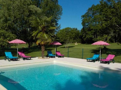a swimming pool with pink and blue chairs and umbrellas at Gîte romantique avec bain à remous privatif près de Sarlat in Saint-Cyprien