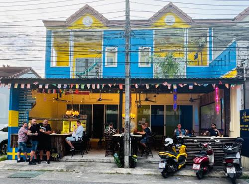 a group of people sitting at tables outside of a restaurant at Sweden Inn Hostel Chalong in Ban Klang