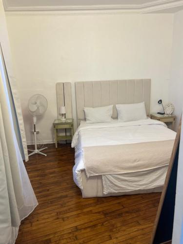 a bedroom with a bed with white sheets and wood floors at Appartement in Montreuil