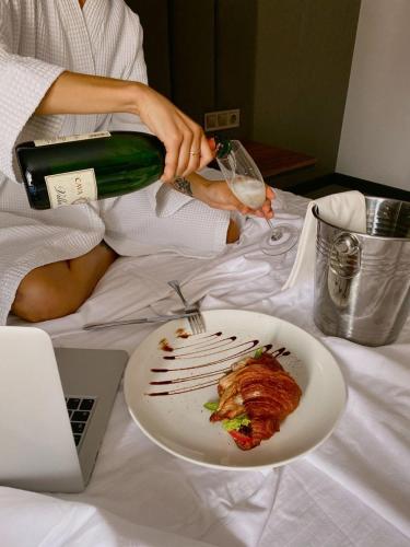 a person sitting on a bed with a plate of food and a bottle of wine at ROYAL SAVOY lUXURY CAMP in Wadi Rum