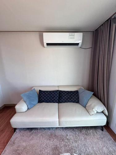 een witte bank met blauwe kussens in een kamer bij Hong Yang in Jeju-stad