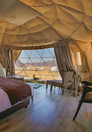 a bedroom with a bed and a view of the desert at ROYAL SAVOY lUXURY CAMP in Wadi Rum