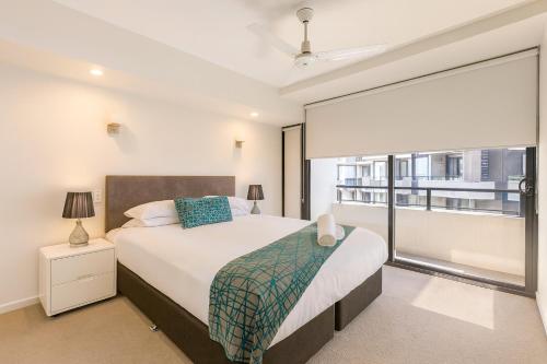 a bedroom with a bed and a large window at Arena Apartments in Brisbane