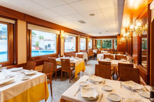 a restaurant with white tables and chairs and windows at Checkin Travé in Figueres