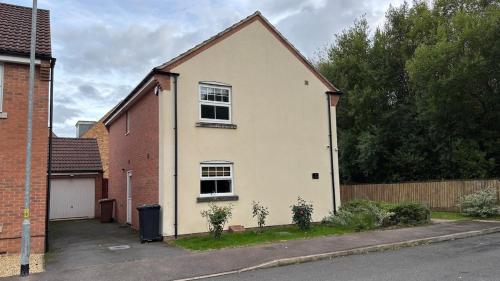 ein weißes Haus mit zwei Fenstern auf einer Straße in der Unterkunft Holiday retreat next to nature in Corby and Weldon