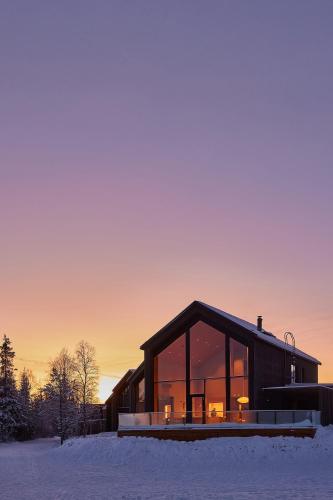 a house in the snow with the sunset in the background at Joiku Luxury Lakeview Chalet in Kolari