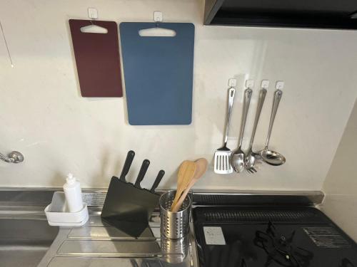 a kitchen counter with utensils hanging on the wall at 伊勢ヒルトップ アパートメント in Ise