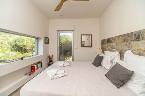 una camera da letto con un grande letto bianco con una finestra di Villa Lucy by PosarelliVillas a Plataniás