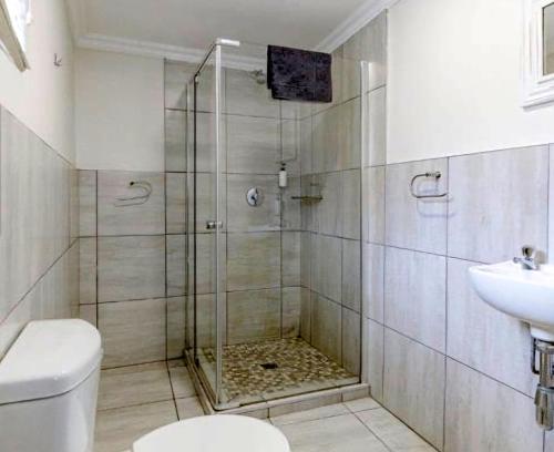 a bathroom with a shower with a toilet and a sink at Banana Beach Club C5 in Port Shepstone