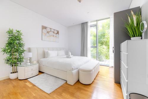 een witte slaapkamer met een wit bed en een groot raam bij Island Paradise - Stylish 1BR on Bluewaters Island in Dubai