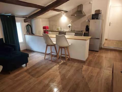 a kitchen with two chairs and a counter with a refrigerator at Minimaliste 10min Futuroscope & Cœur de Poitiers in Buxerolles
