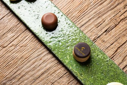 Tres macarrones de chocolate sobre un plato verde en HOTEL de LEN, en Cortina dʼAmpezzo
