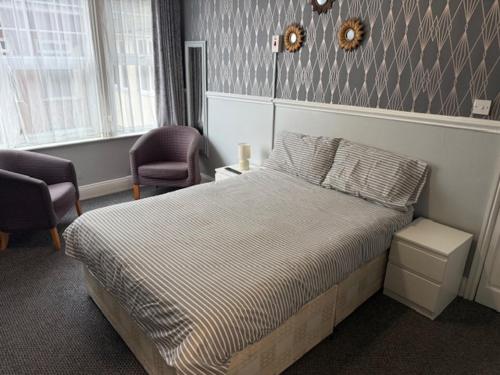 a bedroom with a bed and two chairs in it at majestic hotel in Great Yarmouth