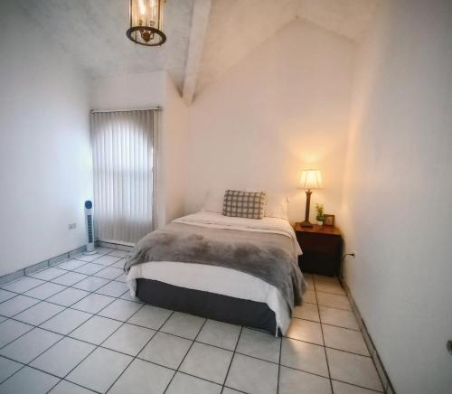 a bedroom with a bed and a lamp on a tiled floor at Casita Patz Ensenada in Ensenada