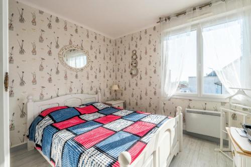 a bedroom with a white bed with a colorful comforter at La Maison Du Bonheur in Fresnay-en-Retz