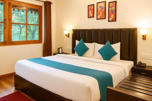 a bedroom with a large bed with blue pillows at Heyan Cedar Woods Nainital in Nainital
