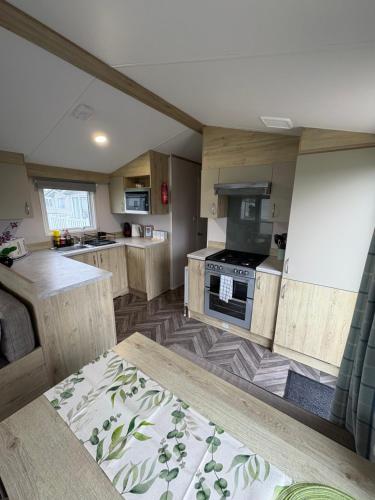 a kitchen with wooden cabinets and a stove at The Restful Rose at Chichester Lakeside in Chichester