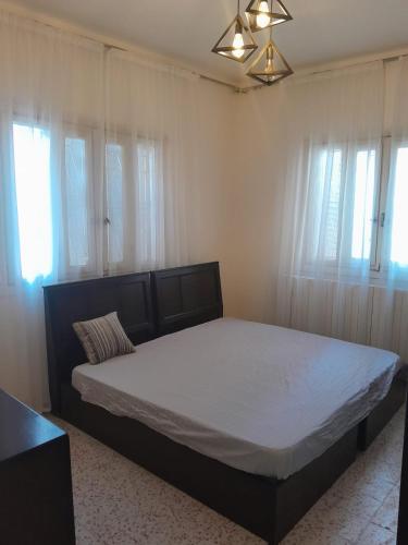 a bedroom with a bed with white sheets and windows at Weibdeh 3b furnished rooms in Amman