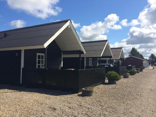 a row of houses with a fence in a driveway at Vejers Family Camping & Cottages in Vejers Strand