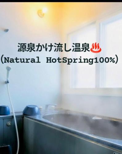 a bathroom with a sign on the wall at 源泉かけ流し温泉付き一棟貸しVilla GENSEN TWO in Yuzawa