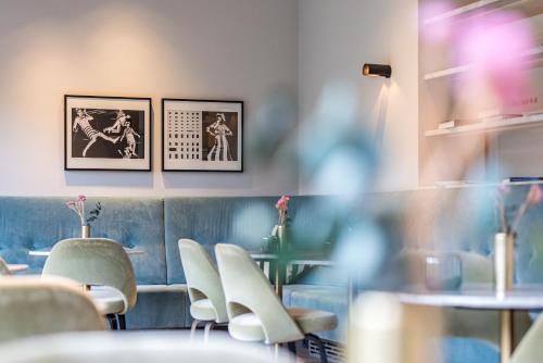 アムステルダムにあるMaison ELLE Amsterdamの白い椅子とテーブルがあり、壁に絵が飾られているレストラン
