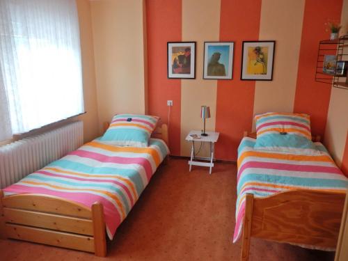 two beds in a room with orange walls at Ferienwohnung Sonnenblume in Leer