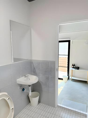 a white bathroom with a sink and a toilet at Yellow Place Sukhumvit Soi 2 - เยลโล เพลส สุขุมวิทซอย 2 Pro in Bang Kapi