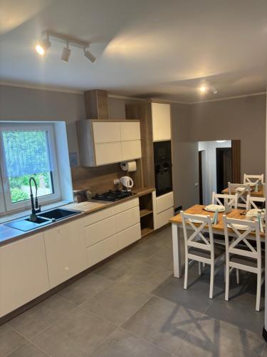 a kitchen with white cabinets and a table and chairs at Nowy Zakątek in Kobyla Góra