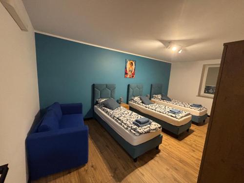 a room with three beds and a blue couch at Nowy Zakątek in Kobyla Góra