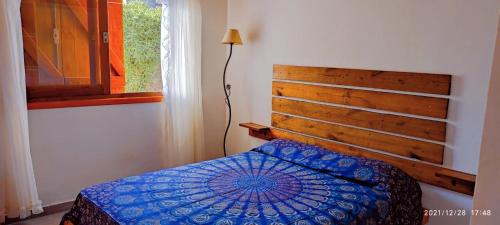 a bedroom with a bed with a wooden headboard and a window at CASA TEMPORADA 2027 PARQUEMAr in Miramar