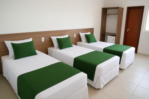 three beds in a room with green and white at Gran Carlo Hotel in Taubaté