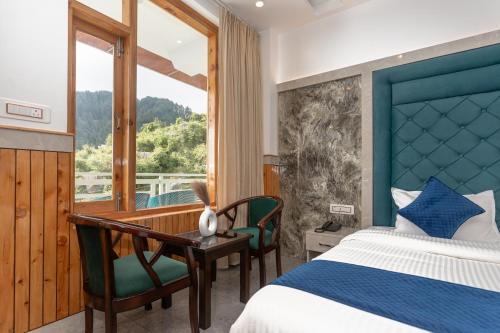 a bedroom with a bed and a desk and a window at Tara Van in Dharamshala