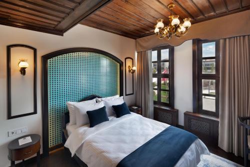 a bedroom with a bed and a chandelier and windows at Sırçalı Hotel in Meram