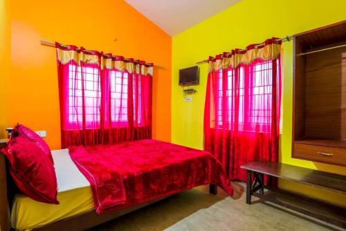um quarto com cortinas vermelhas e uma cama com uma mesa em Butterfly homestay em Ooty