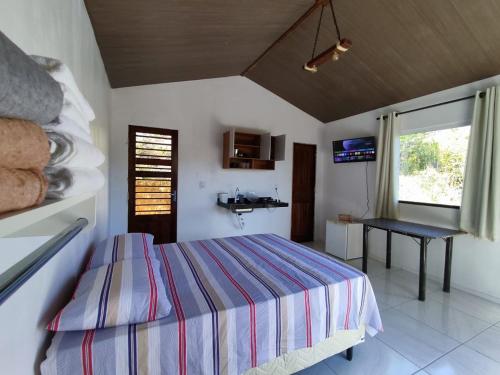 a bedroom with a bed and a table and a window at Chalé Bella Vista in Mulungu
