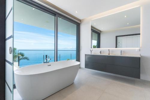 ein weißes Badezimmer mit einer großen Badewanne und einem großen Fenster in der Unterkunft Villa Zenha by Atlantic Holiday in Ribeira Brava
