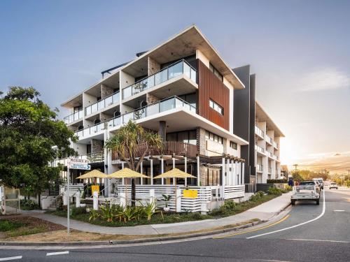 an apartment building with umbrellas on a street at The Sebel Brisbane Margate Beach in Redcliffe